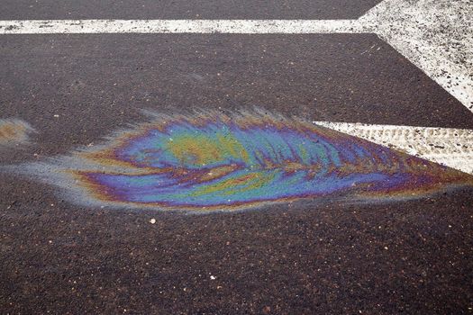 Colored oil stains in the car park, the color of the gasoline stain on the pavement road as a texture or background.Abstract rainbow effect background