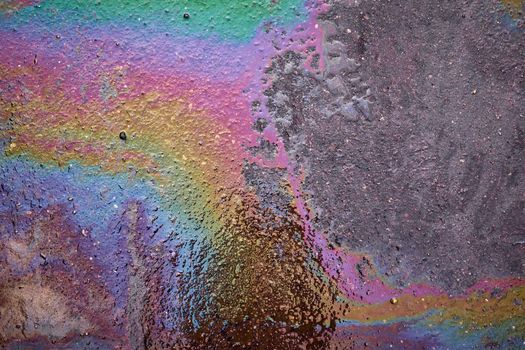 Colored oil stains in the car park, the color of the gasoline stain on the pavement road as a texture or background.Abstract rainbow effect background