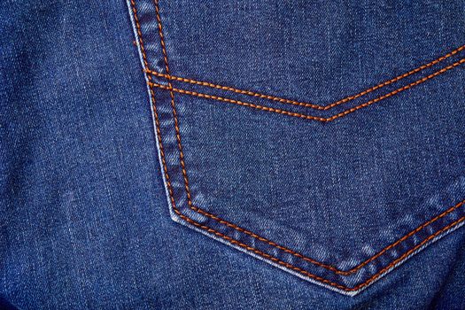 Blue denim jeans background pocket with seam and orange thread stitches. Casual urban classic fashion