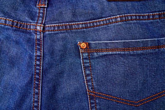 Blue denim jeans background pocket with seam and orange thread stitches. Casual urban classic fashion