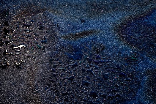 Oil stain on wet asphalt caused by a leak under a car or truck.Environmental petrol oil pollution.