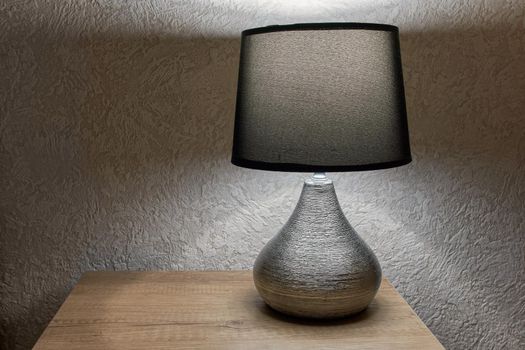 tylish lamp on table against wall, space for text.