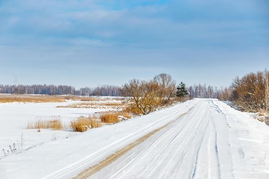 Snowy road along the lake on a bright sunny day