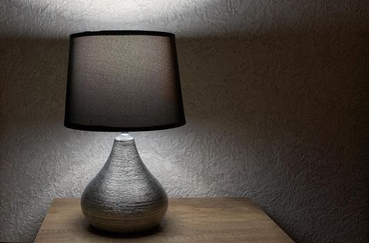 tylish lamp on table against wall, space for text.