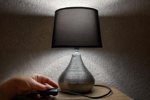 A woman's hand turns on or off a table lamp in the bedroom, beautiful, luxurious modern design.