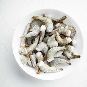 Frozen raw uncooked tiger prawns, shrimps set, on white stone surface, top view flat lay, square format
