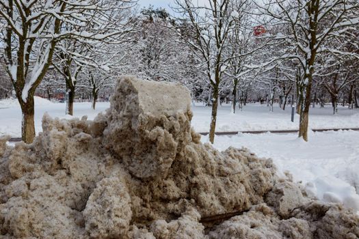 Big Pile Of Dirty Melting Snow In A Parking Lot. The concept of snow removal. Soft selective focus