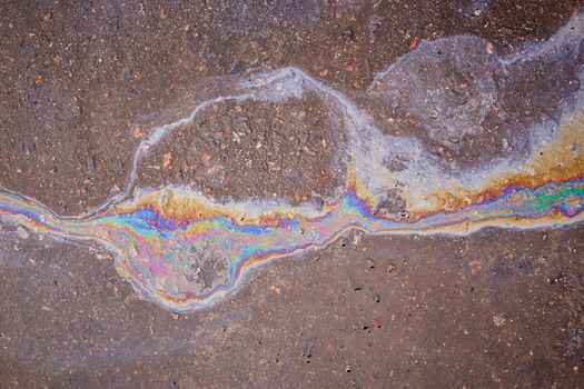 Gasoline flows on the asphalt surface. Iridescent stains of gasoline.