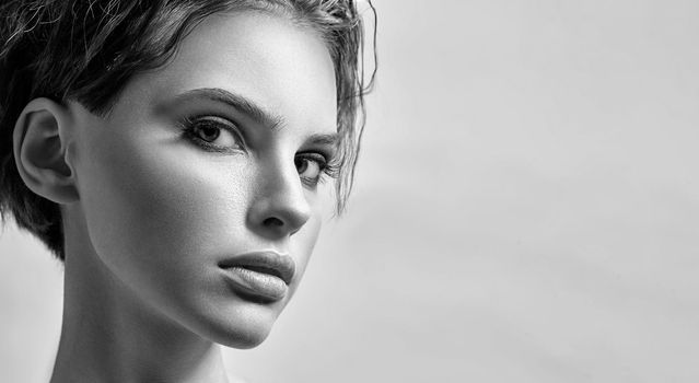 Monochrome portrait of a young attractive woman in the studio on a light background