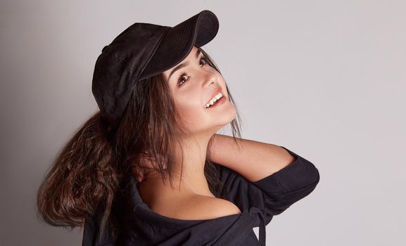 Very attractive young woman in a cap posing in the studio on a gray background
