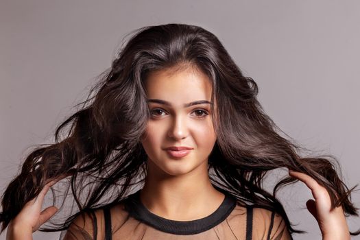 Portrait of sexy woman with beautiful make-up and long curly hair. Girl holding her hair with her hands and looking at the camera