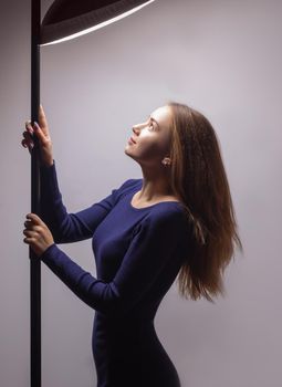 Young woman adjusts light in studio from lighting equipment