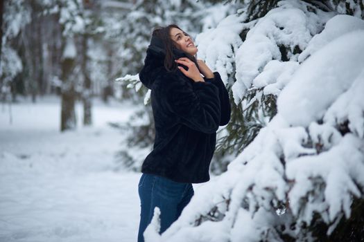 Young woman rejoices in the first snow in the forest