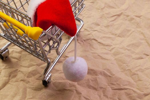 Shopping trolley and red Santa Claus cap. Winter holidays. Merry christmas and happy new year concept.