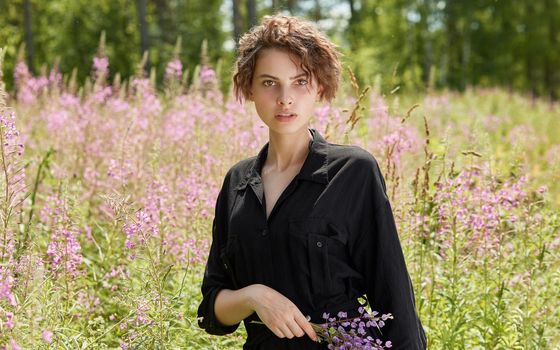 A young woman against the background of blooming Ivan-tea on a bright sunny summer day.The concept of youth