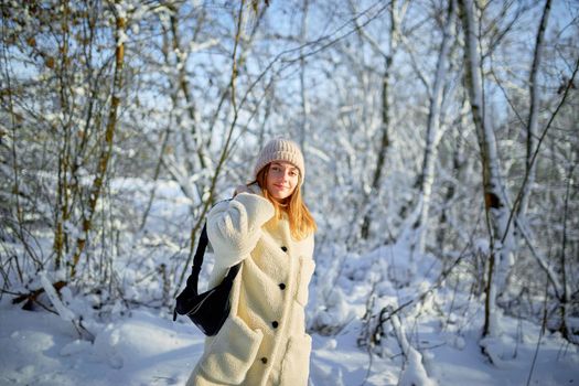 Young woman walks on the background of a snowy forest. Selective focus