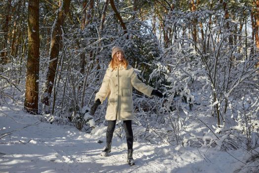 Happy woman walking in snow outdoors nature. Joyful young person relaxing on an outdoor walk activity in snowy forest landscape