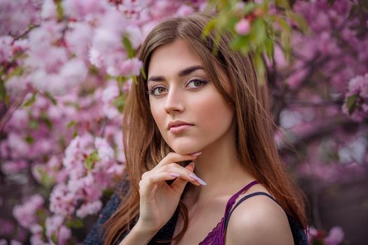 beautiful young woman in blooming cherry blossoms garden in early spring