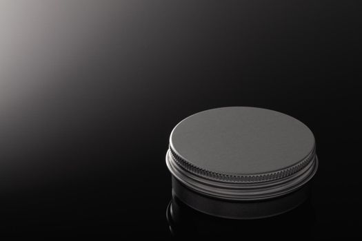 Silver metal containers for cosmetics isolated on the black glass desk.
