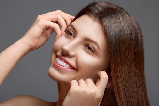 Portrait of happy smiling beautiful young woman touching skin, showing beautiful white smile