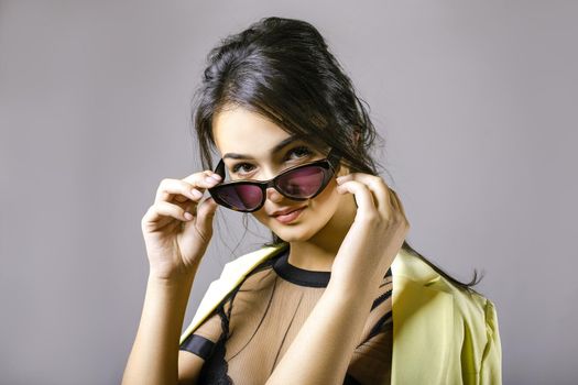 Portrait of a happy beautiful young woman in stylish sunglasses. The girl adjusts glasses