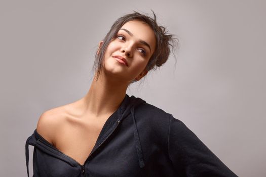 Young woman in sports t-shirt showing shoulder on gray background in studio