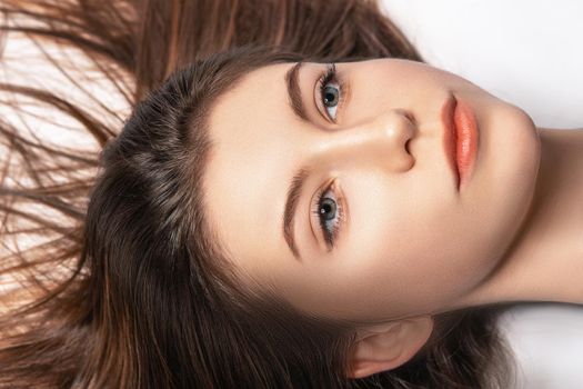 Portrait of a young woman with her hair spread while lying in a studio
