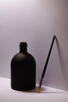 Still life with luxury black glass of Rrum and paintbrush in artist atelier.