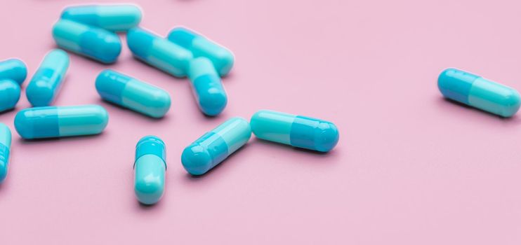Blue capsule pills on pink background. Pharmaceutical industry. Capsule pill administration. Non drug therapy topics. Health budget management. Pharmacy shop banner. Capsule pill manufacturing. 