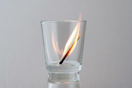 Fire from a burning match in a transparent glass. Concept, symbol