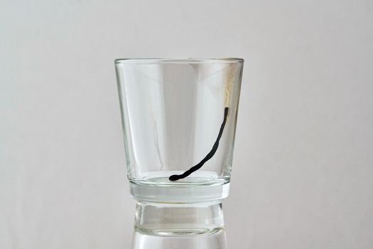 The remains of a burnt match lie in a transparent glass. Close up