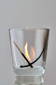 Two charred matches burn out in a transparent glass. Concept, symbol