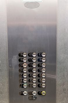 Shiny metal panel with floor number buttons. Elevator control panel. Place for text