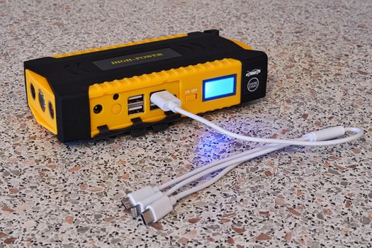 Yellow power bank with a universal cable for different types of charging. Close up