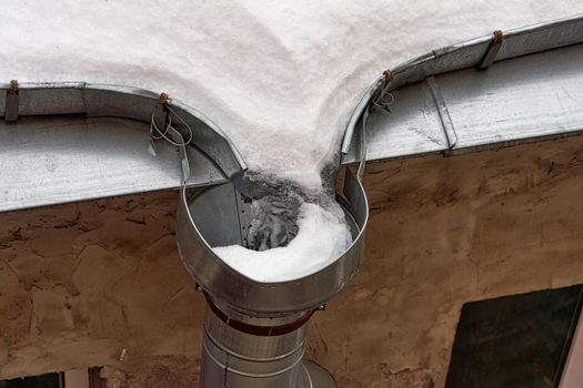 Frozen roof gutter clogged with snow and ice. Winter drainage problems