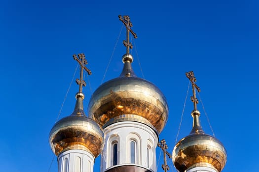 Church golden domes with Orthodox crosses against the blue sky. Close up