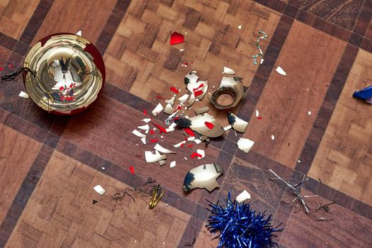 Broken Christmas tree toy and colored glass shards on the floor. Close up