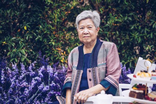 asian old elderly female elder woman resting relaxing in lavender flower garden. senior leisure lifestyle