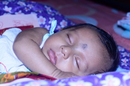 Close up face of a cute sleeping newborn baby. Closeup portrait of a Sweet just born infant boy captured in sleepy mood drowsy eyes. Hand on Chin. Front view. Child care kid background image.