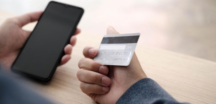 Online payment,Man's hands holding a credit card and using smart phone for online shopping.