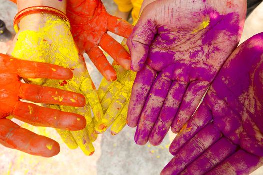 Young people with colorful powder in hands at holi festival in India celebrated with different colors. Holi hands, colorful hands illustration. Close up view.