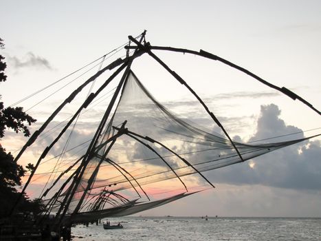 Sunset at tropical beach. Ocean coast landscape with Chinese fishing nets silhouette at Cochin. Kerala backwaters South India