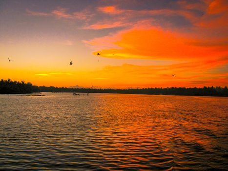 Sunset sky background. Red orange color clouds-cape in sunset sky at dusk. Landscape Beauty in nature horizon over lake water. Dramatic atmospheric mood.