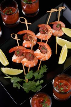 Appetizer of shish kebab with shrimps and chorizo sausages with barbecue sauce in a glass