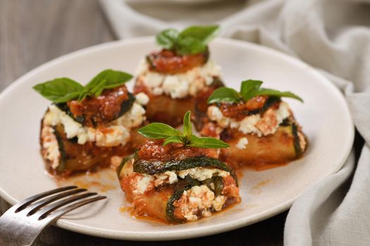 Baked zucchini rolls stuffed with ricotta and basil under tomato-onion-carrot gravy 