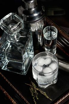 A glass of gin and tonic cooled with ice on a tray standing on the books
