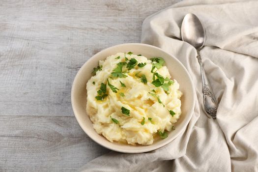 A plate of mashed potatoes poured with melted butter and seasoned with greens