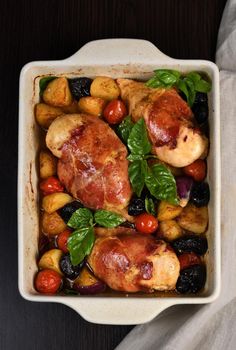 Chicken breast stuffed with goat cheese with spinach, wrapped in prosciutto, with slices of baked potatoes, tomatoes, and dried prunes.