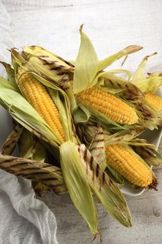 Delicate, juicy corn on the cob in husk cooked grilled