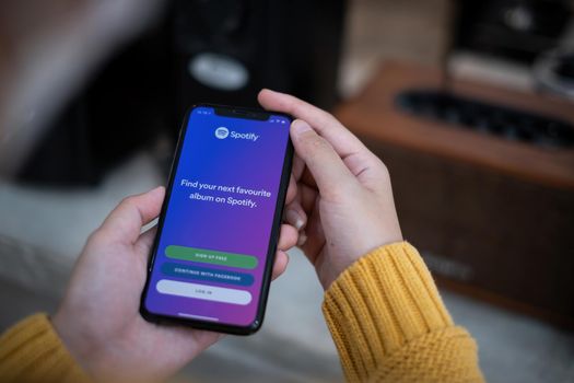 CHIANG MAI, THAILAND APR 14 2021 : Smartphone and using Spotify application on the screen and sync to speaker via bluetooth. Spotify is a music streaming platform developed